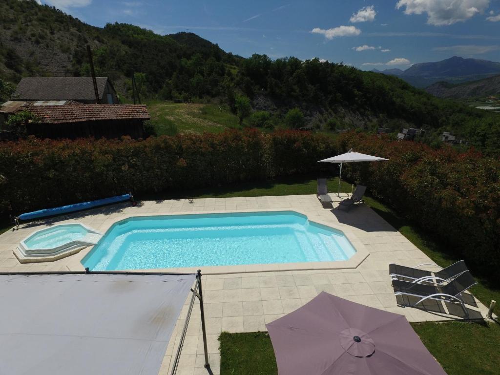 una piscina con 2 sombrillas en un patio en Chambres d'hôtes La Dorgisane, en Venterol