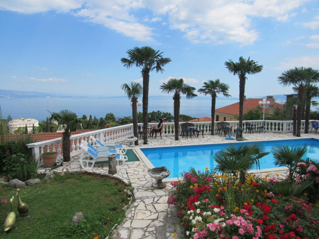 a resort with a swimming pool and palm trees at Apartments Villa Palme in Opatija