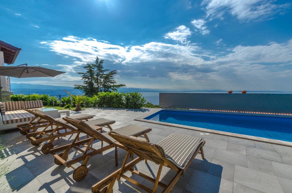 a patio with chairs and a swimming pool at Apartments Villa Sonja in Matulji