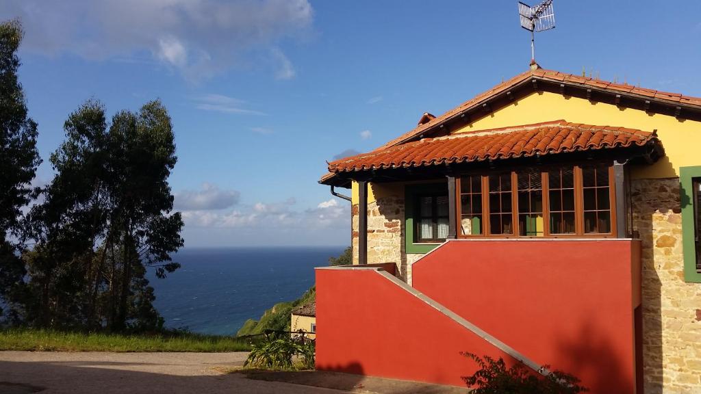 una casa en una colina con el océano en el fondo en Turismo rural El Piensu, en Villaviciosa