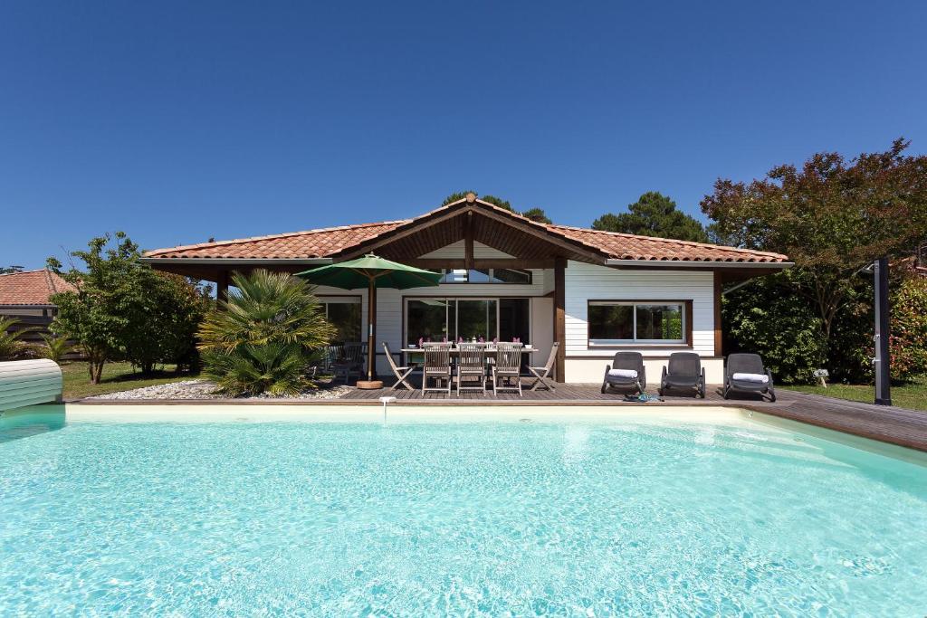 una casa con piscina frente a una casa en Madame Vacances Villas La Prade en Moliets-et-Maa