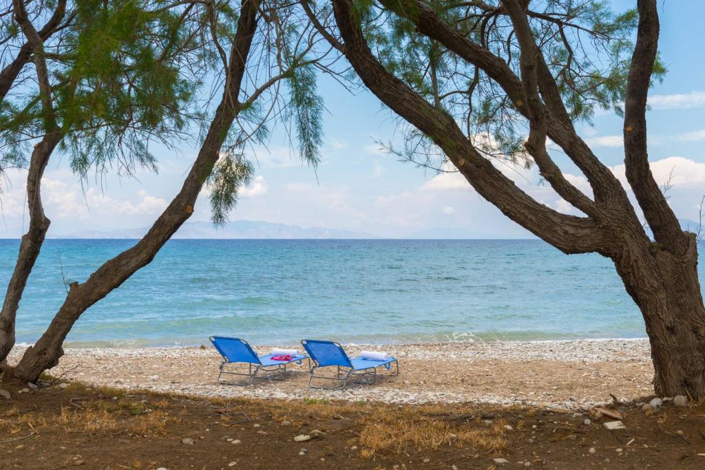 dwa niebieskie krzesła siedzące na plaży w pobliżu wody w obiekcie Annabel Apartments w mieście Theologos