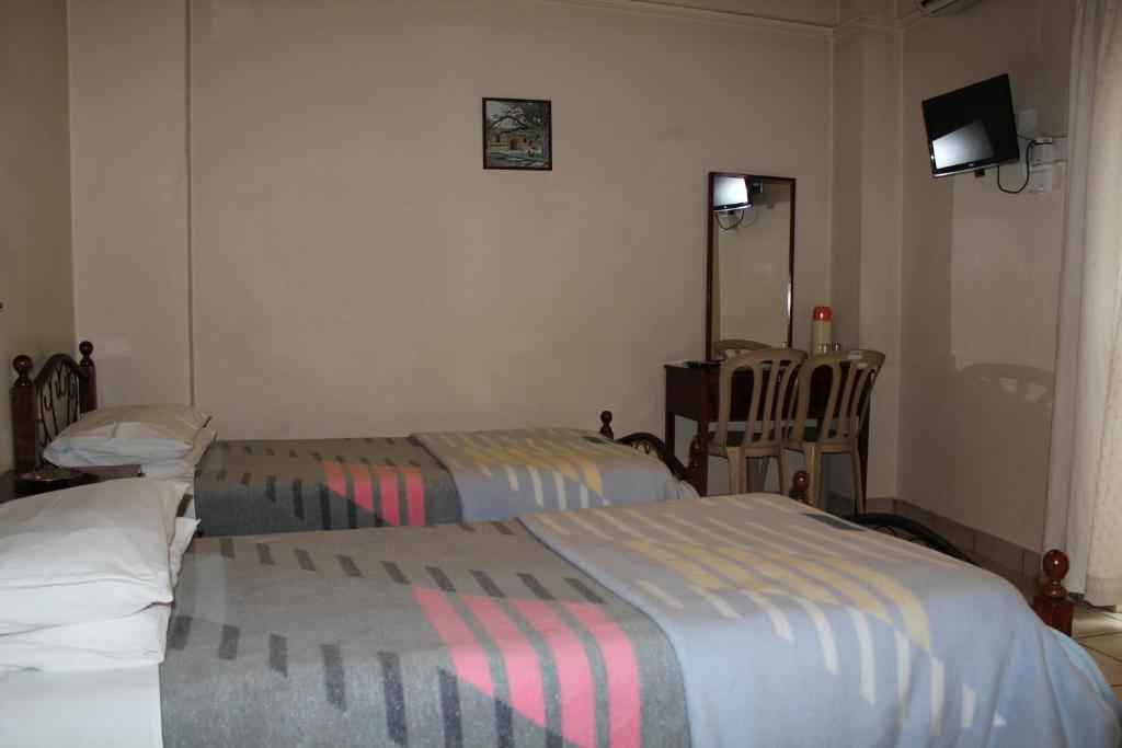 a hotel room with two beds and a mirror at Delphi Hotel in Nicosia