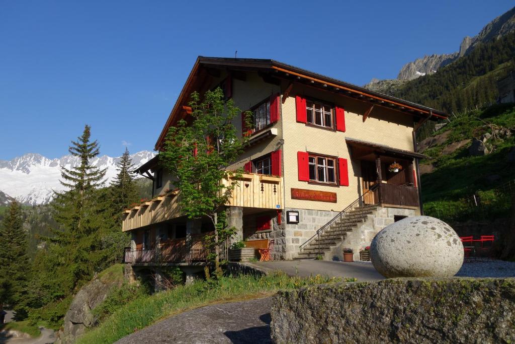 un grand bâtiment avec des ornements rouges sur une montagne dans l'établissement Gasthaus Göscheneralp, à Göschenen