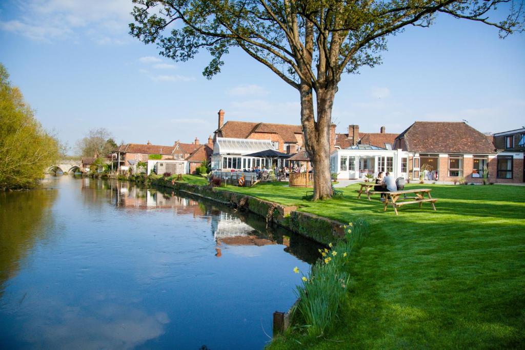 un río en una ciudad con edificios y una persona sentada en un banco en The Legacy Rose & Crown Hotel en Salisbury