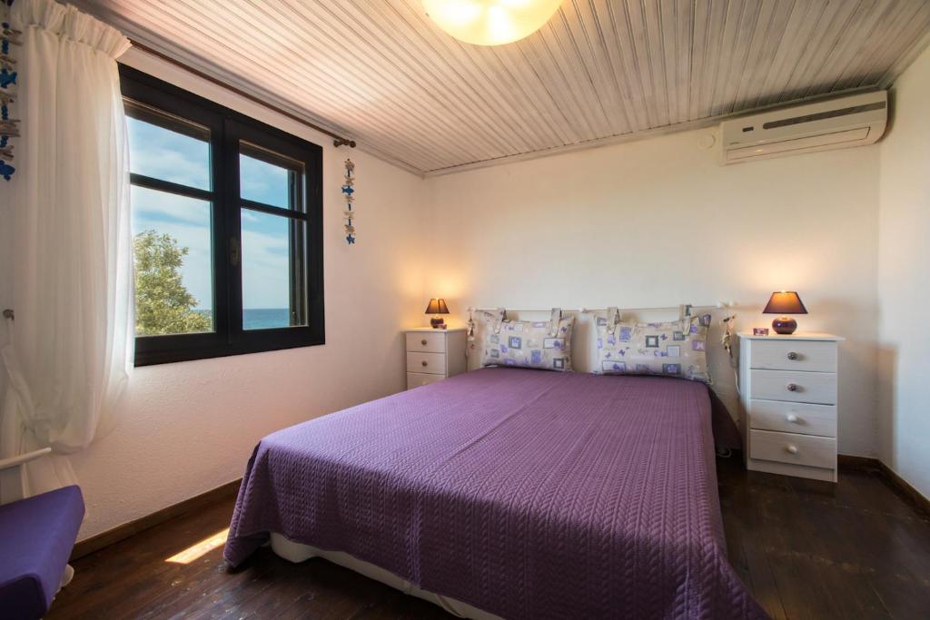 a bedroom with a purple bed and a window at Ktima Delmare Pantazara in Nea Skioni
