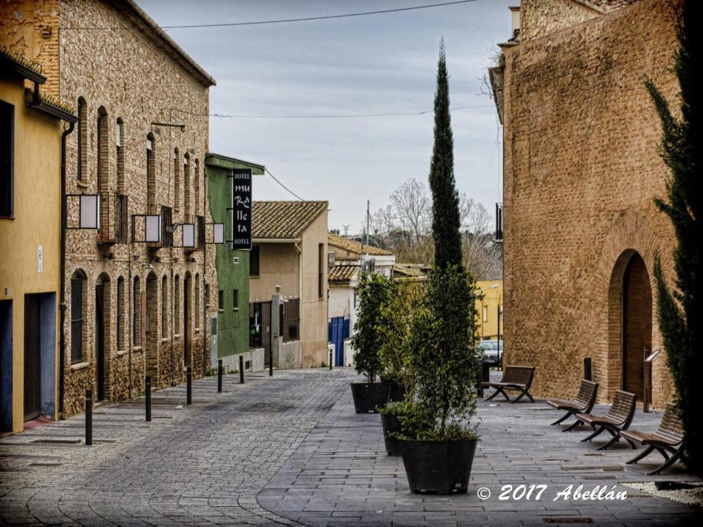 una calle en una ciudad con bancos y edificios en Hotel Muralleta, en Ribarroja del Turia