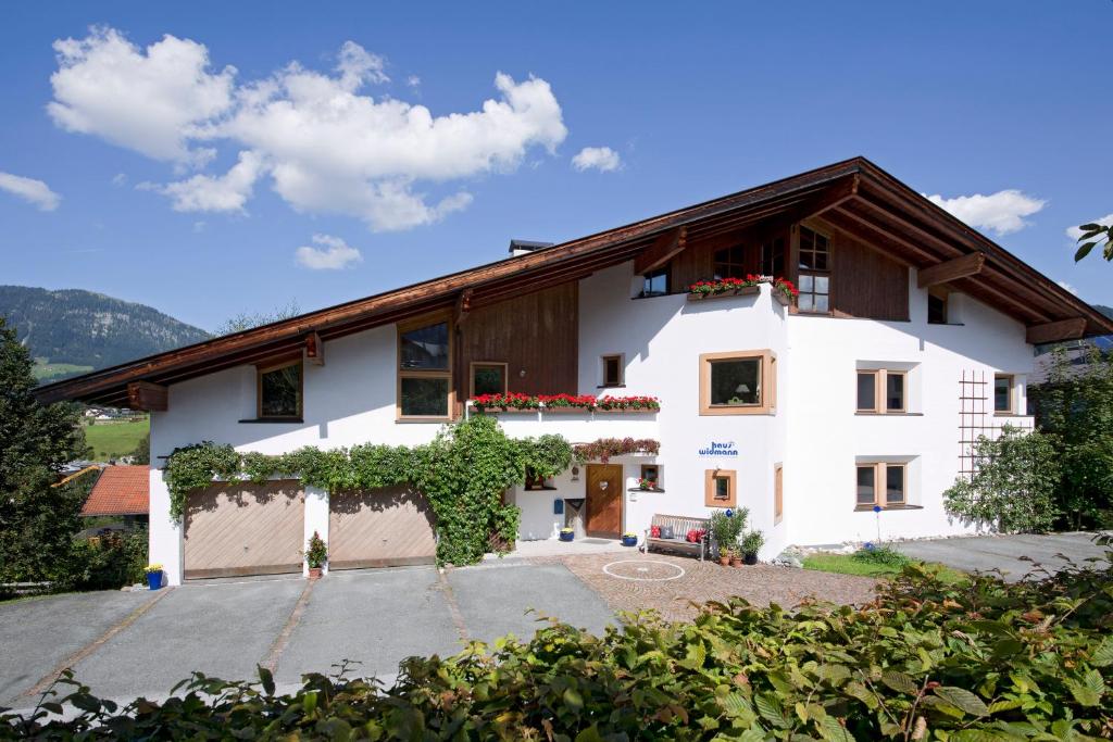 a white house with a wooden roof at Haus Widmann in Fieberbrunn
