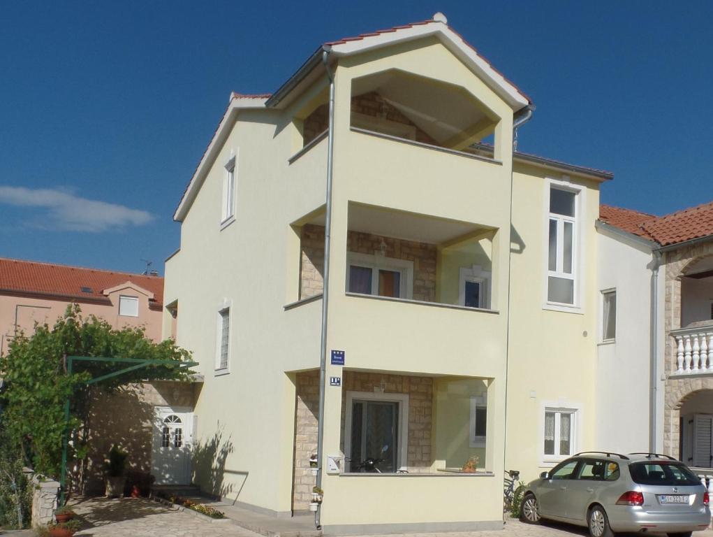 a white house with a car parked in front of it at Apartments gabrijel in Vodice