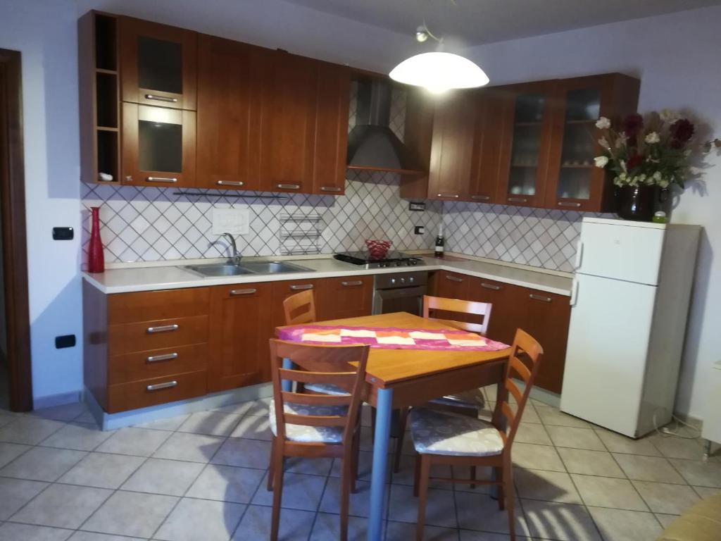 cocina con mesa, sillas y nevera en Trilocale La Corte en Montaquila