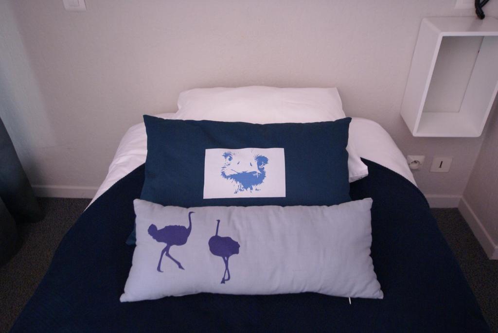 a bed with blue and white pillows on it at Hotel de la Placette Barcelonnette in Barcelonnette