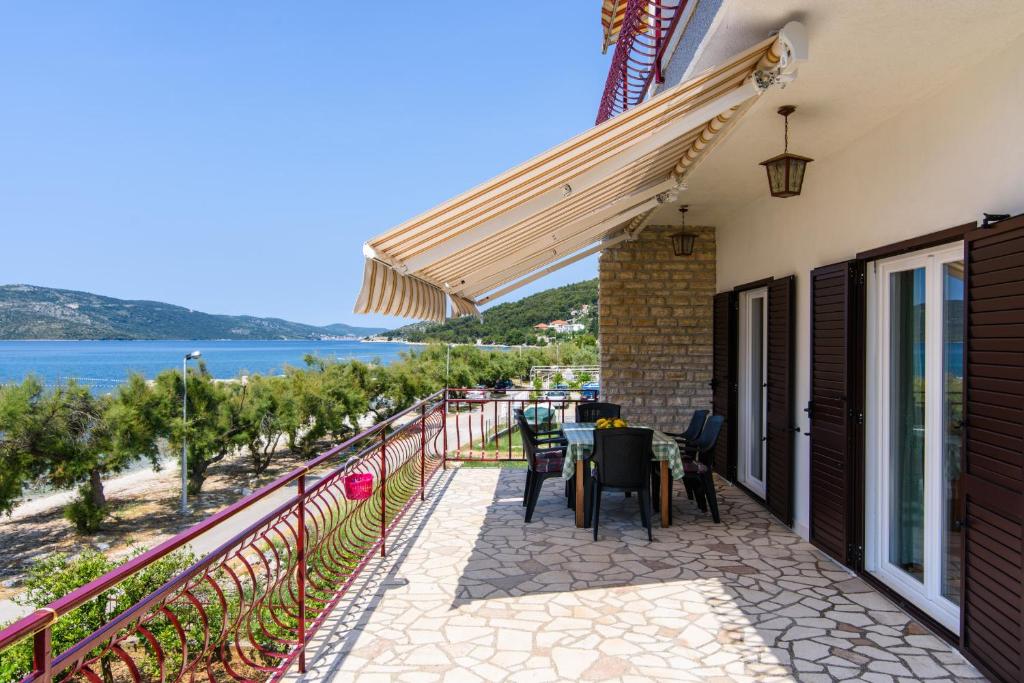 a balcony with a table and chairs and a view of the ocean at Apartment Vinka i Mijo in Seget Vranjica