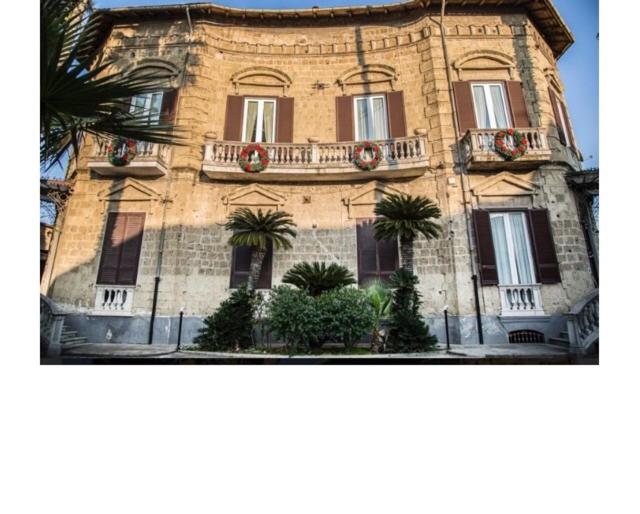 un grand bâtiment en briques avec des palmiers devant lui dans l'établissement Bnb Villa Lendi, à Frattamaggiore