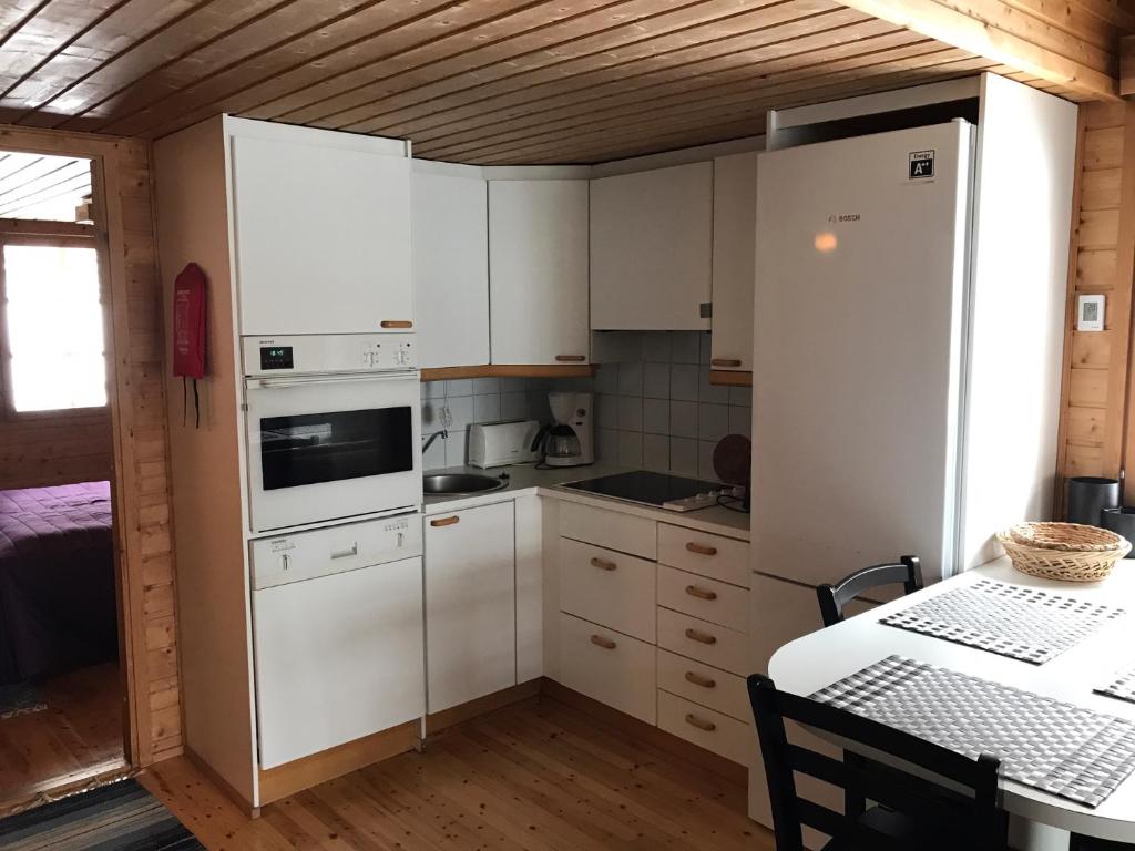 a small kitchen with white cabinets and a table at Panoraama 3 in Saariselka