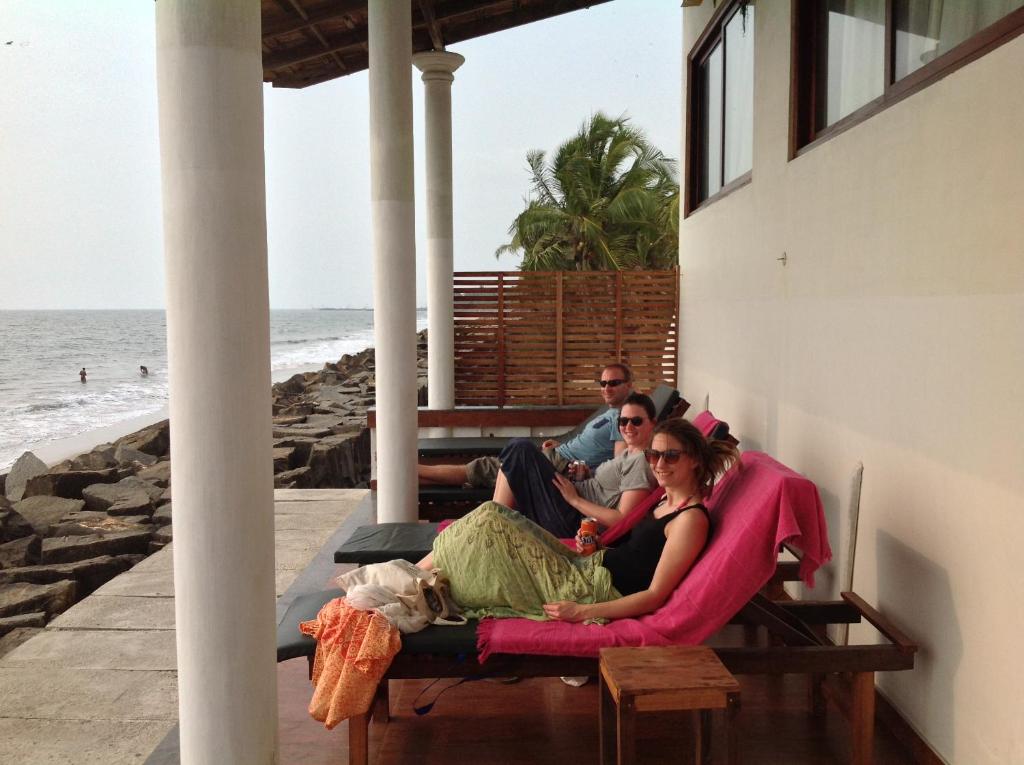 un gruppo di persone seduti su un portico vicino alla spiaggia di Cherai Onetree Retreat a Cherai Beach