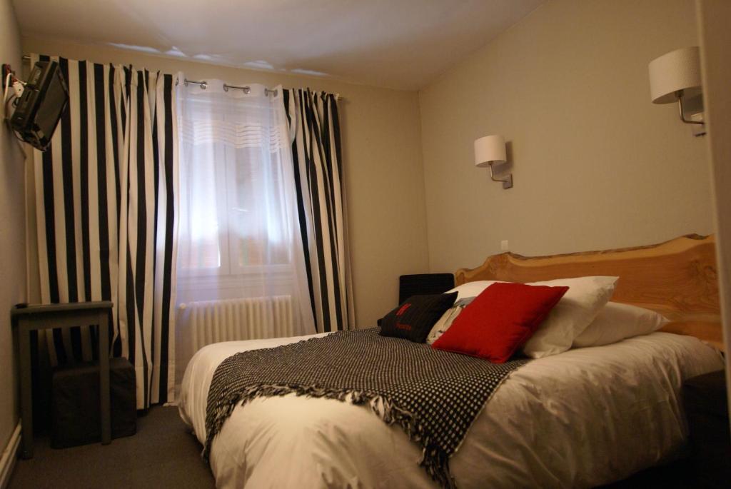 a bedroom with a bed and a window with curtains at Hotel de la Placette Barcelonnette in Barcelonnette