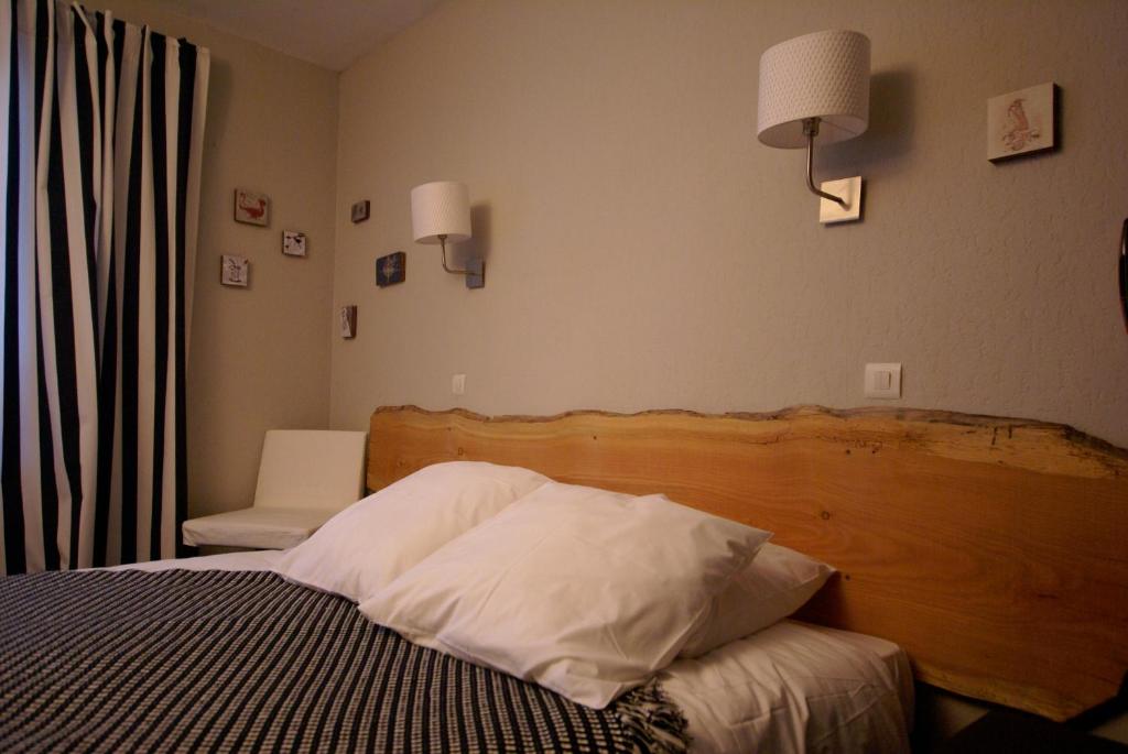 a bedroom with a bed with a wooden head board at Hotel de la Placette Barcelonnette in Barcelonnette