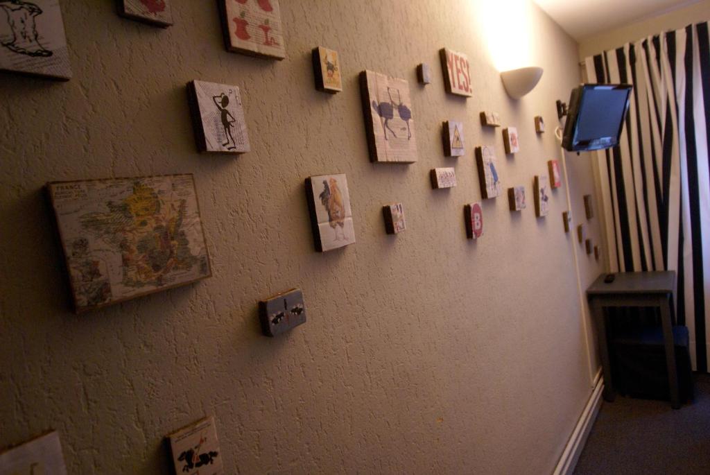 a wall with cards and pictures on it at Hotel de la Placette Barcelonnette in Barcelonnette
