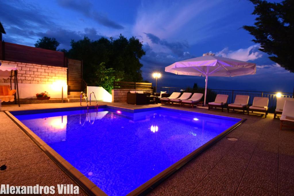 una piscina con illuminazione blu in un cortile posteriore di notte di Alexandros Villa Luxury Achiilion Corfu a Perama