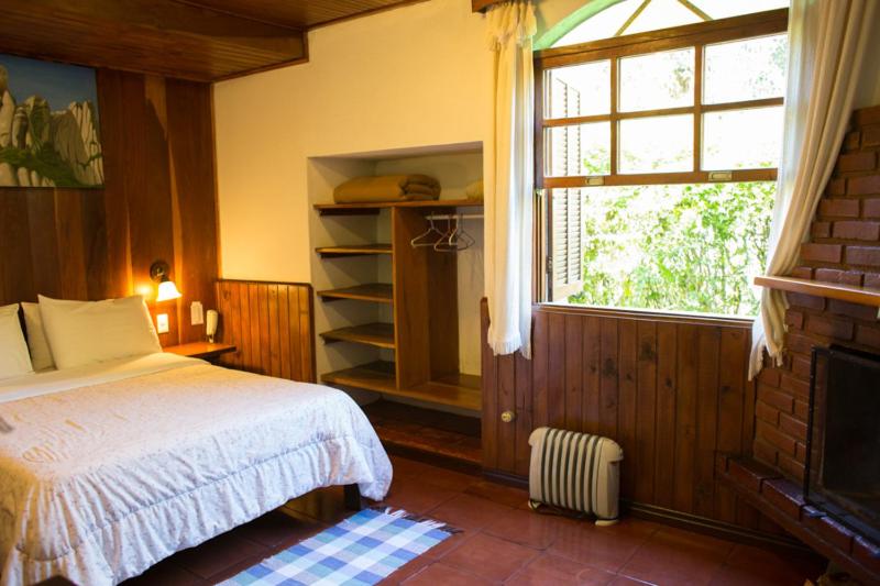 a bedroom with a bed and a window at Pousada Montserrat in Visconde De Maua