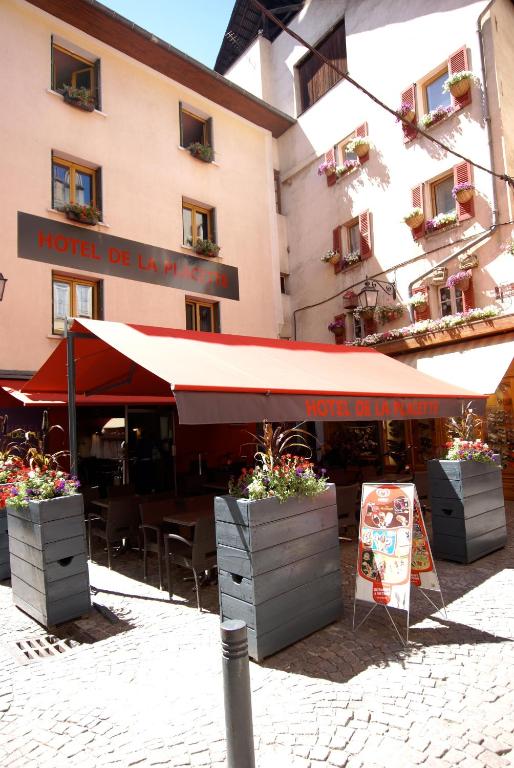 a restaurant with a red umbrella in front of a building at Hotel de la Placette Barcelonnette in Barcelonnette