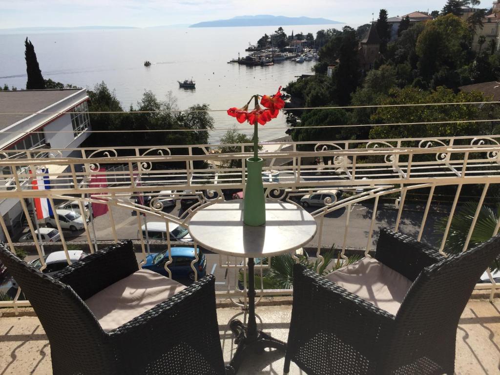 einen Tisch mit einer roten Blume auf dem Balkon in der Unterkunft Studio Apartment Antonija in Opatija