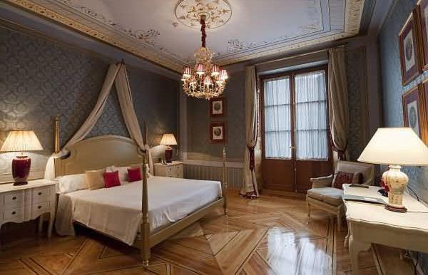 - une grande chambre avec un lit et un lustre dans l'établissement Posada Real Los Cinco Linajes, à Arévalo