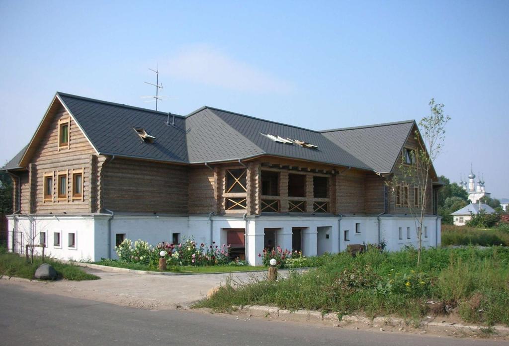 a large wooden house with a gambrel roof at Stromynka Hotel in Suzdal