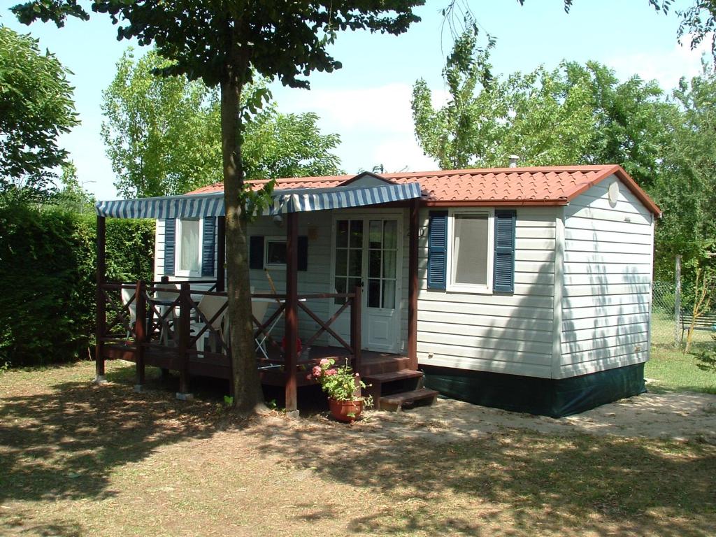a small shed with a porch and a tree at Mobilhome Angel in Cavallino-Treporti