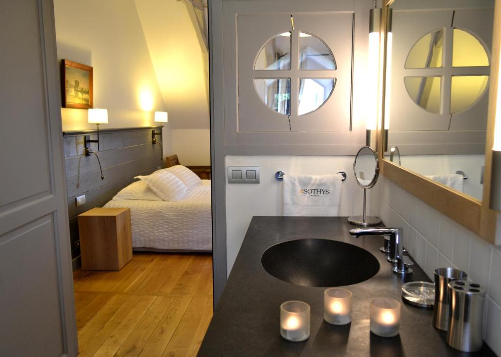 a bathroom with a sink and a bedroom with a bed at La Maison Des Jardins in Auriac