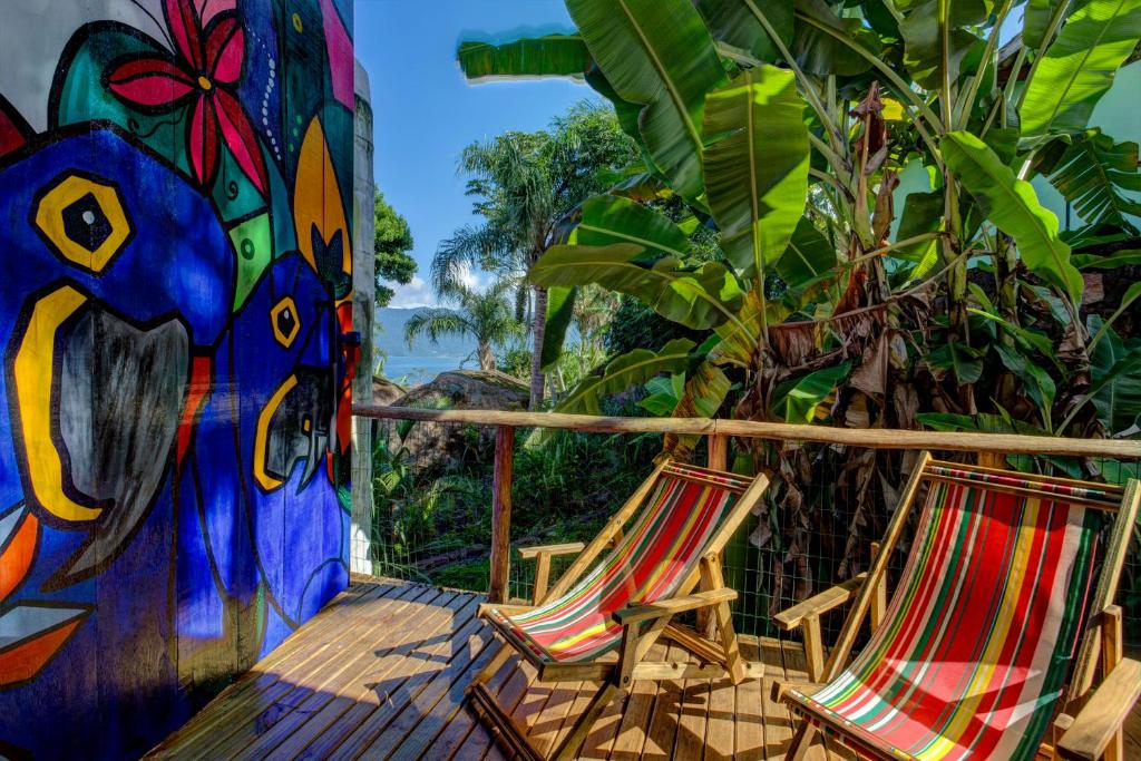 2 sillas sentadas en una terraza con un mural en Sea View Colorful House, en Ilhabela