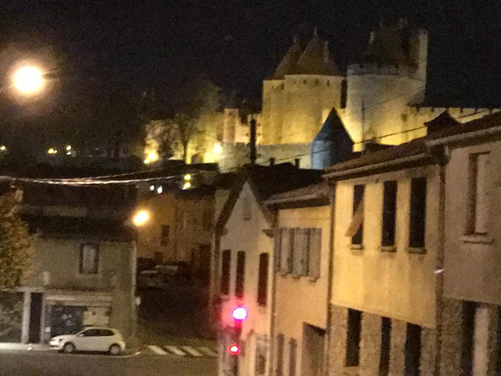 eine Ampel in einer Stadt in der Nacht mit einem Schloss in der Unterkunft Appartements "Le 102" in Carcassonne