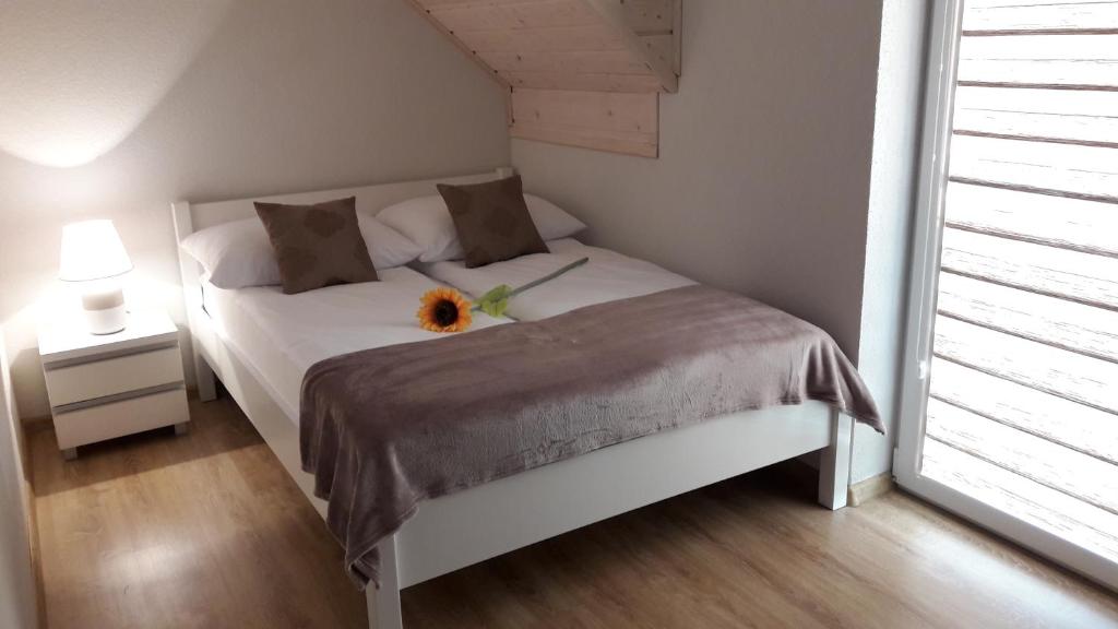 Un dormitorio con una cama blanca con un girasol. en Domki Marina en Ustronie Morskie