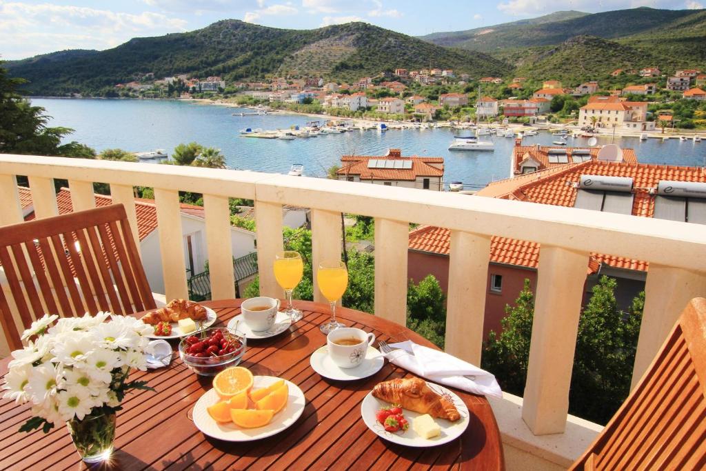una mesa con comida en el balcón con vistas al agua en Villa Vrbat, en Seget Vranjica