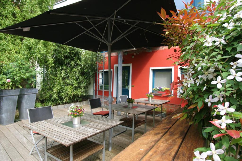 un patio con mesas, sillas y una sombrilla en Hotel Verdi en Rostock
