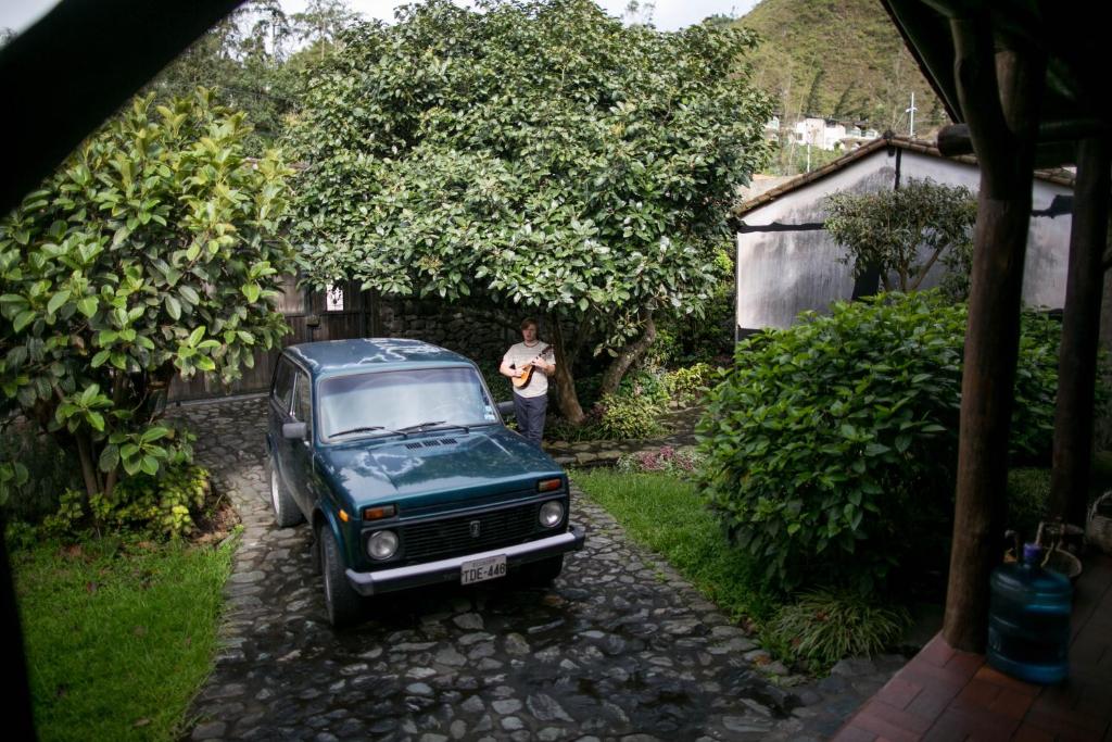 a man standing next to a green truck parked in a driveway at Hospedaje Higueron in Baños