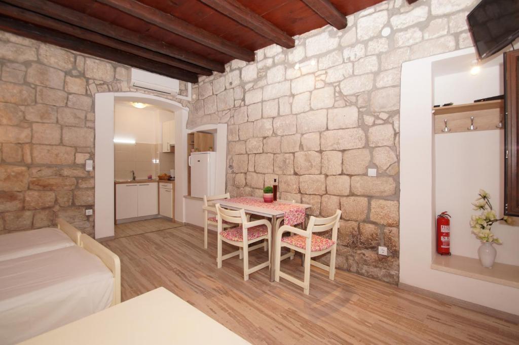 Habitación con mesa y sillas en una pared de piedra. en Apartment Chupa, en Korčula