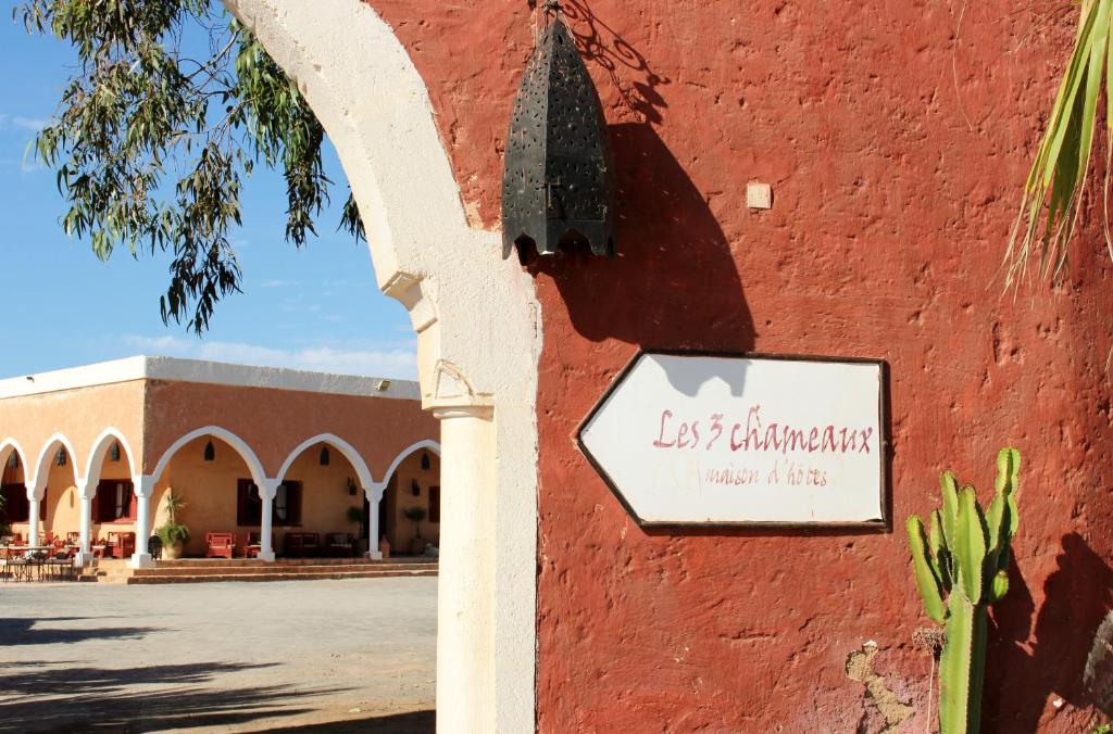 ein Schild an der Seite eines roten Gebäudes in der Unterkunft Hotel De Charme Les 3 Chameaux 4 étoiles in Mirleft