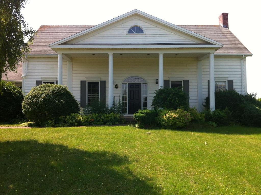 a white house with a grass yard at Seaview White House in Stratford