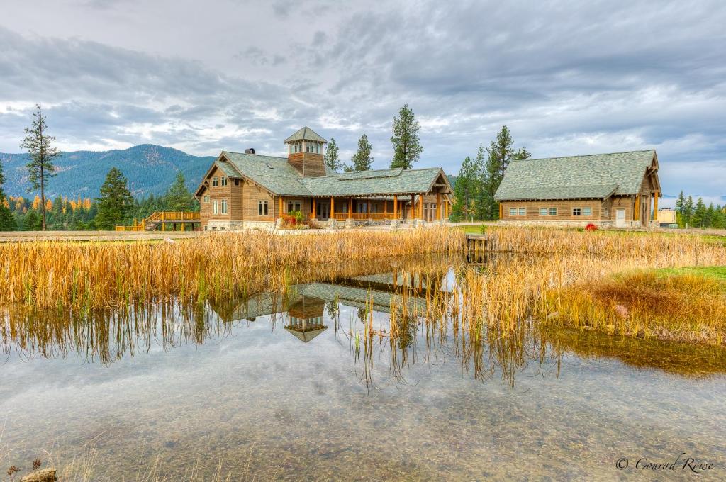 a large wooden house sitting next to a lake at The Lodge at Trout Creek Bed and Breakfast in Trout Creek