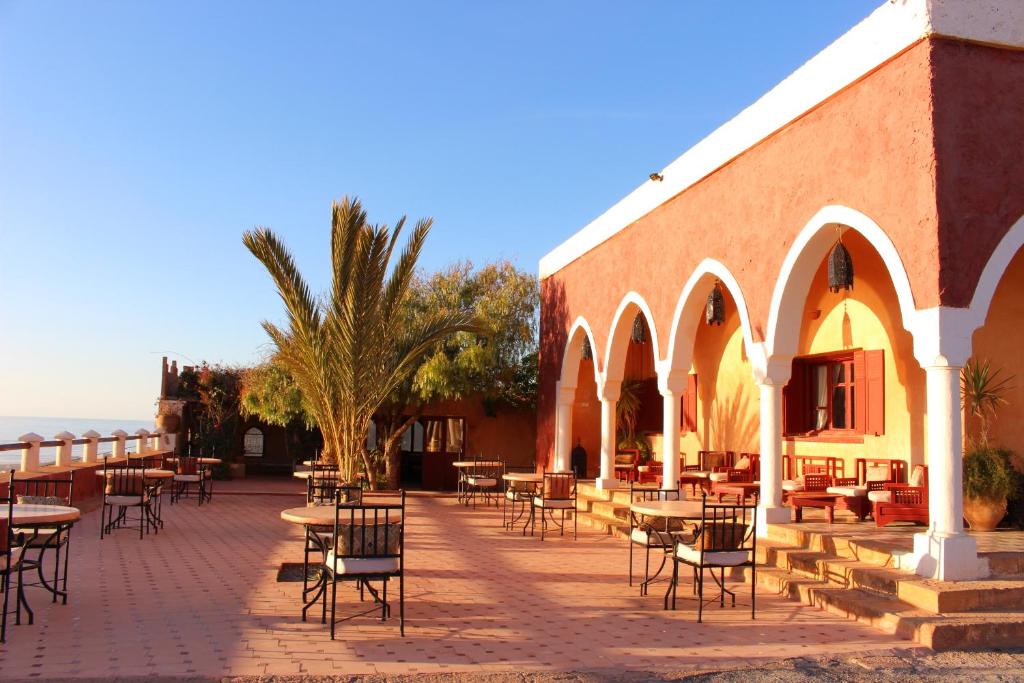 a patio with tables and chairs in front of a building at Hotel De Charme Les 3 Chameaux 4 étoiles in Mirleft