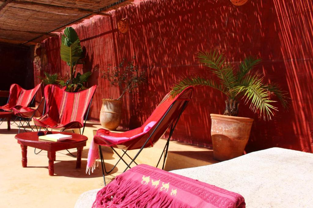 a room with red chairs and plants in it at Hotel De Charme Les 3 Chameaux 4 étoiles in Mirleft