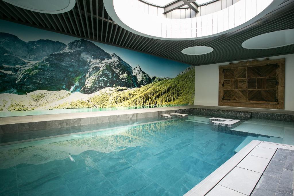 a swimming pool with a mountain mural on the wall at Giewont Krupówki SPA in Zakopane