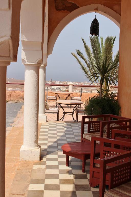a porch with benches and a view of the beach at Hotel De Charme Les 3 Chameaux 4 étoiles in Mirleft