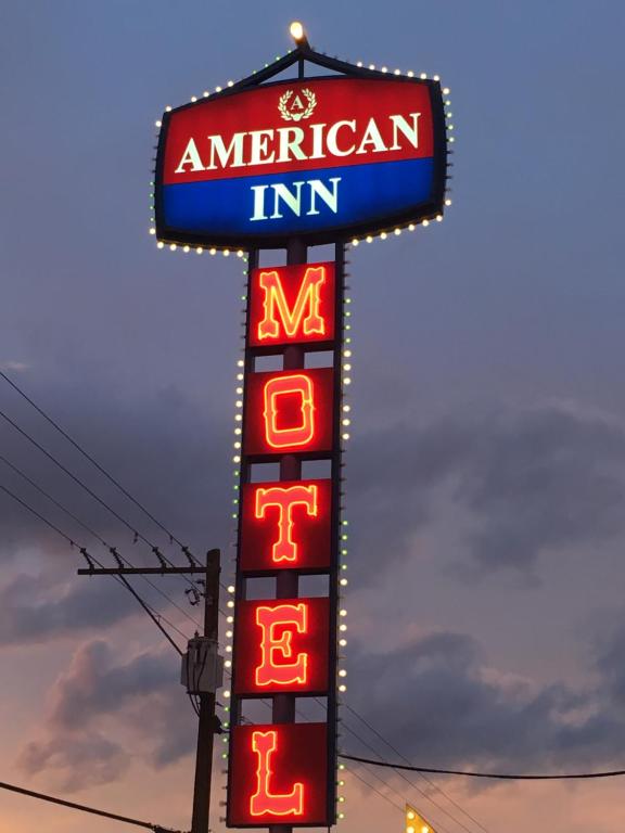 a sign for an american inn with neon signs at American Inn in Las Vegas