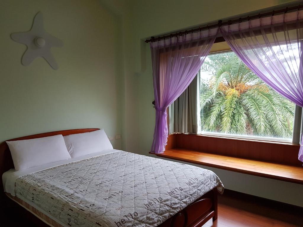 a bedroom with a bed and a window with purple curtains at Lake Villa Homestay in Dongshan