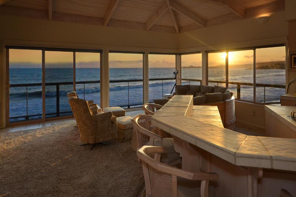 Habitación con una mesa grande, sillas y el océano. en Villa Vista, en Santa Cruz