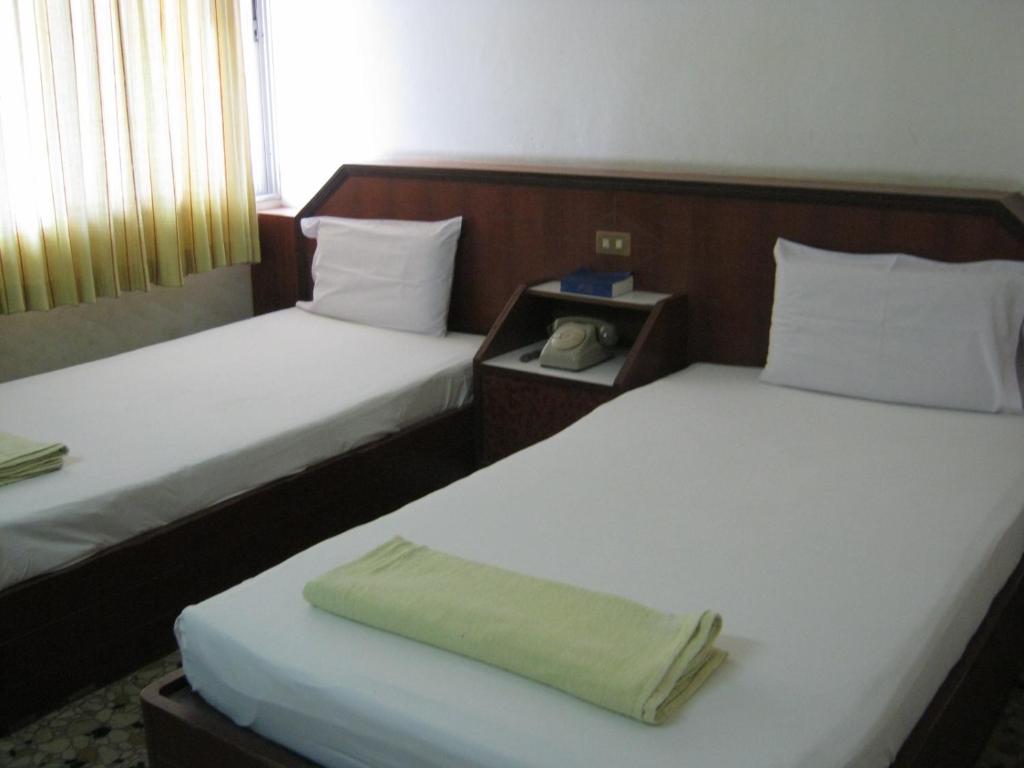 Dos camas en una habitación de hotel con un teléfono. en Ho Fah Hotel, en Phatthalung