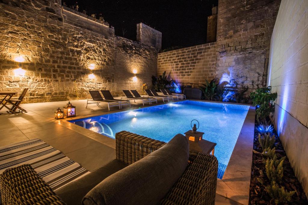 - une piscine avec des canapés et des chaises à côté d'un bâtiment dans l'établissement BB De Rohan, à Żebbuġ