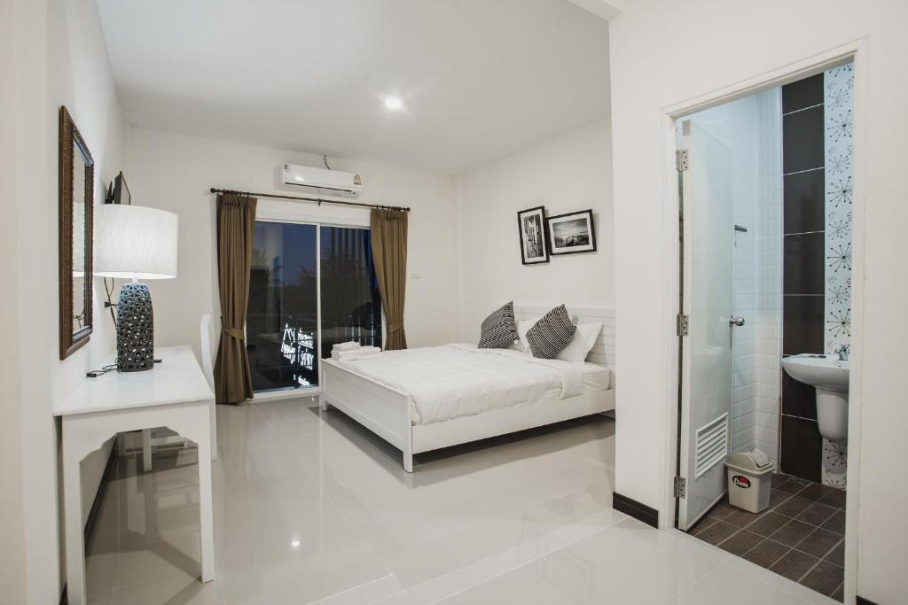 a white bedroom with a bed and a sink at Banjan Stay in Udon Thani